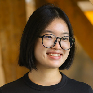 Smiling young woman wearing round glasses. Team Consulting employee portrait.