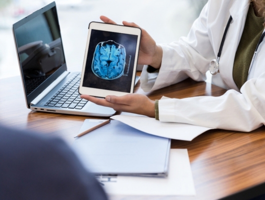 doctor using software to show MRI scan on a tablet