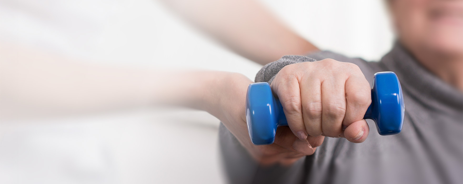 Hand holding blue weight during rehabilitation