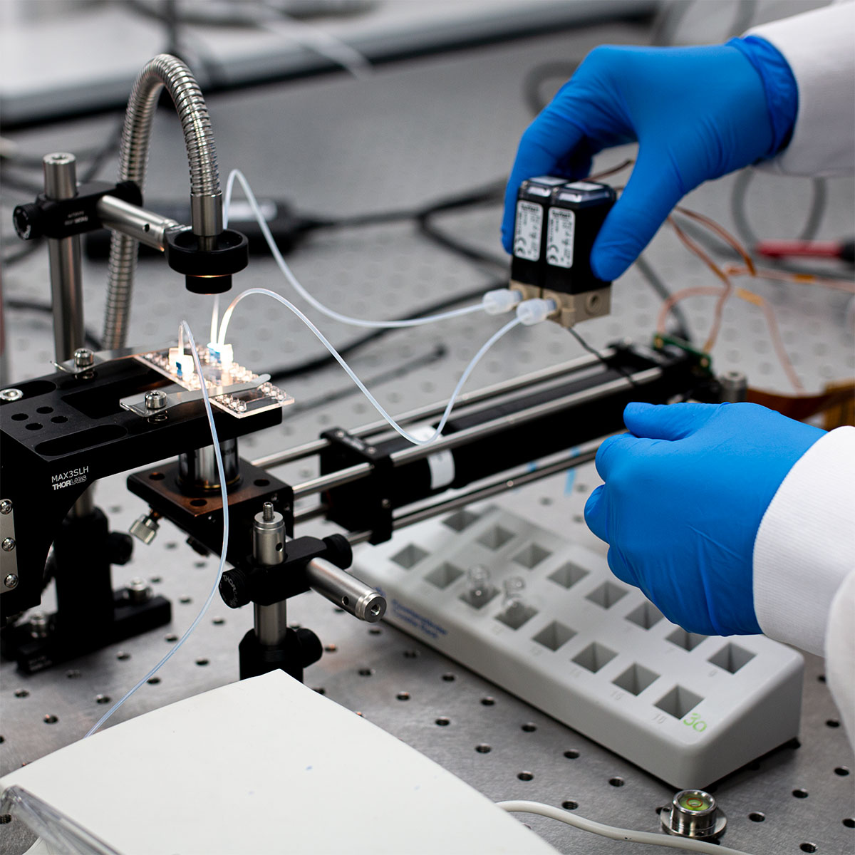 Gloved hands holding batteries over cell sorter rig