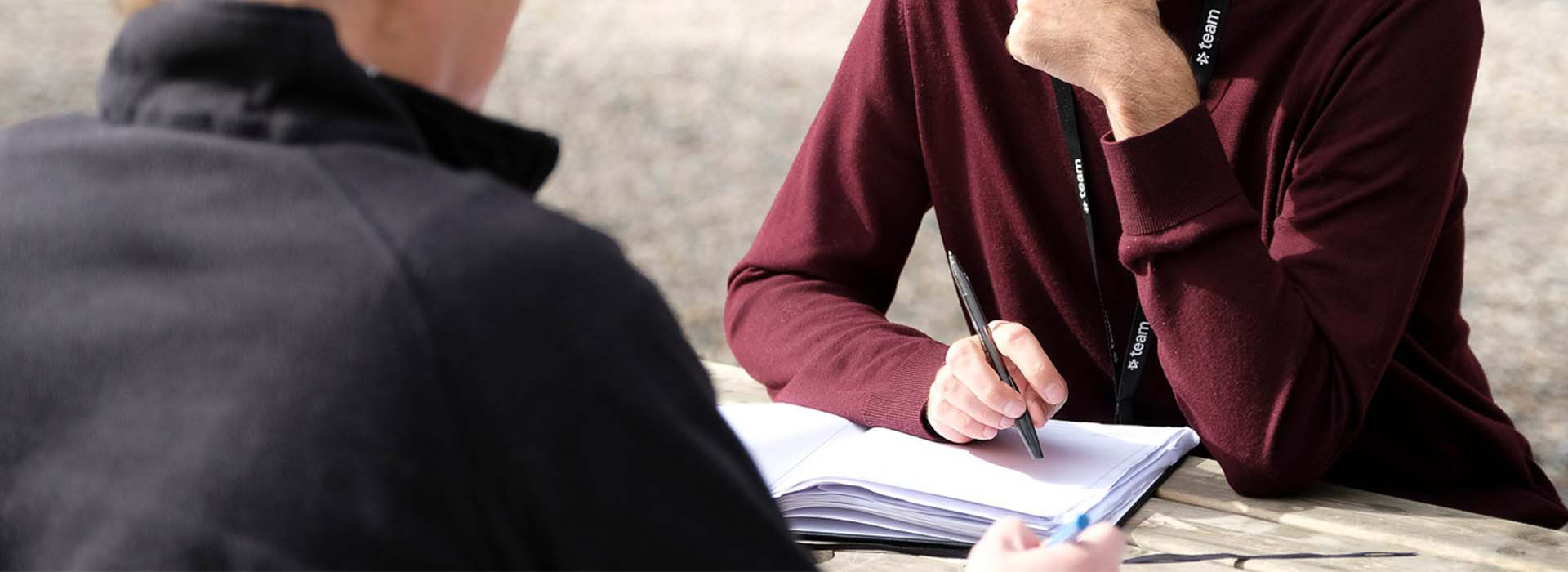 Person holding pen over paper banner