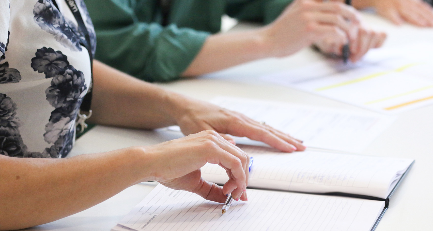 Hand holding pen over notepad banner image