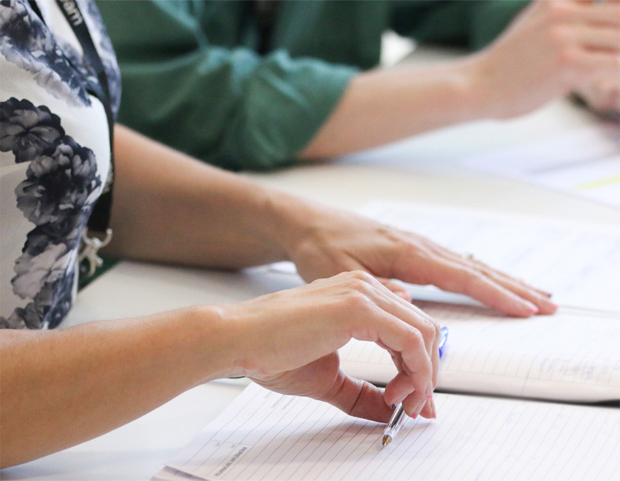 Hand holding pen over notepad mobile banner image